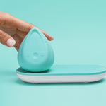 Evii clitoral vibrator by Biird in color mint with charging tray and hand