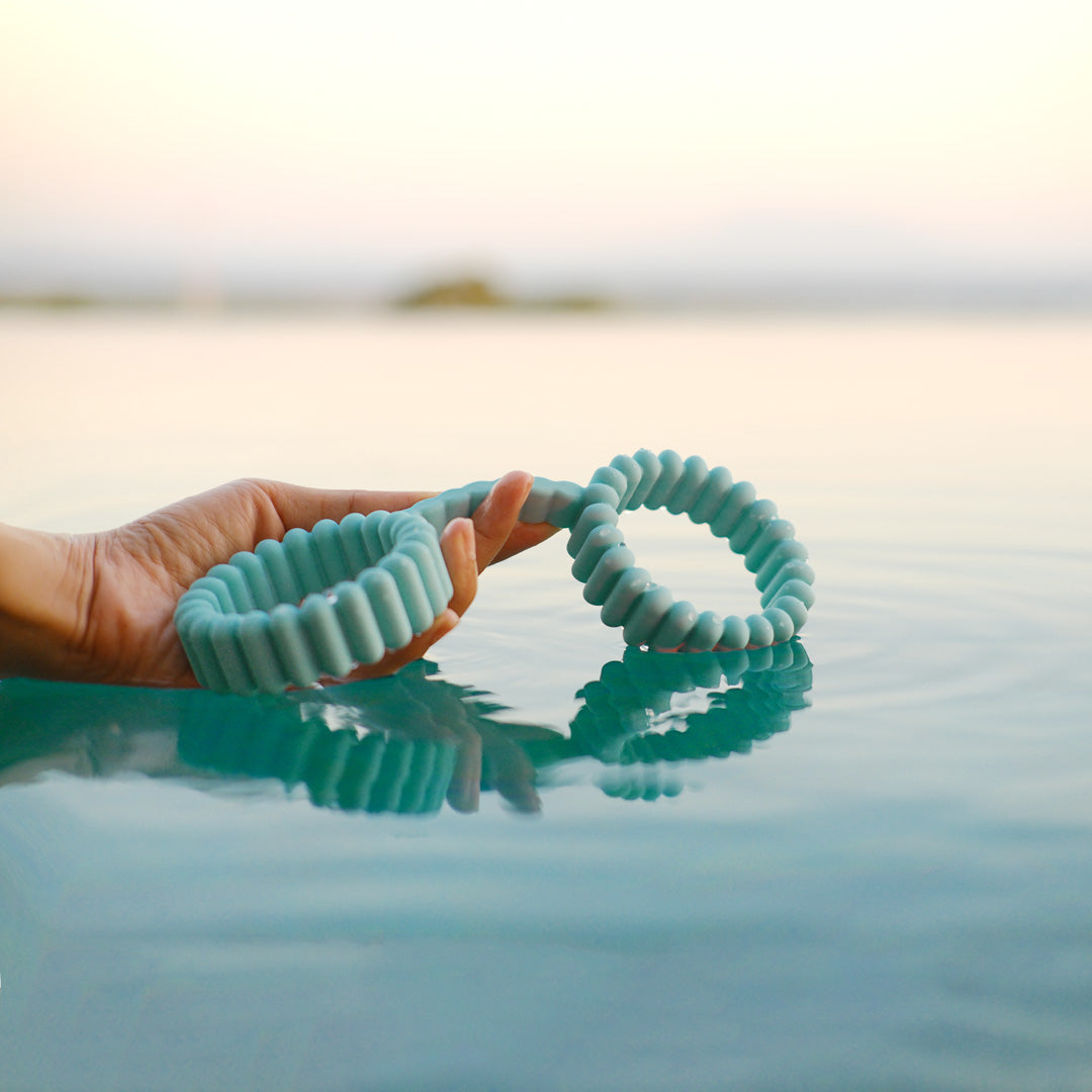 Playful Handcuffs for couples play by Biird in turquoise with hand in water