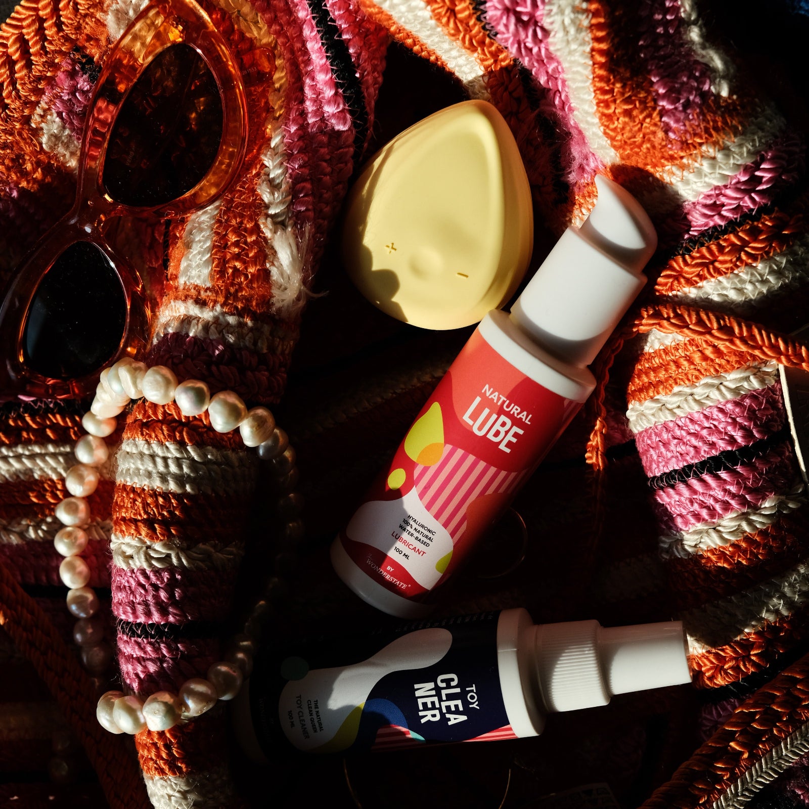 Personal care items including a tube of lip balm, a bottle of nail polish, and a bar of soap on a textured surface.